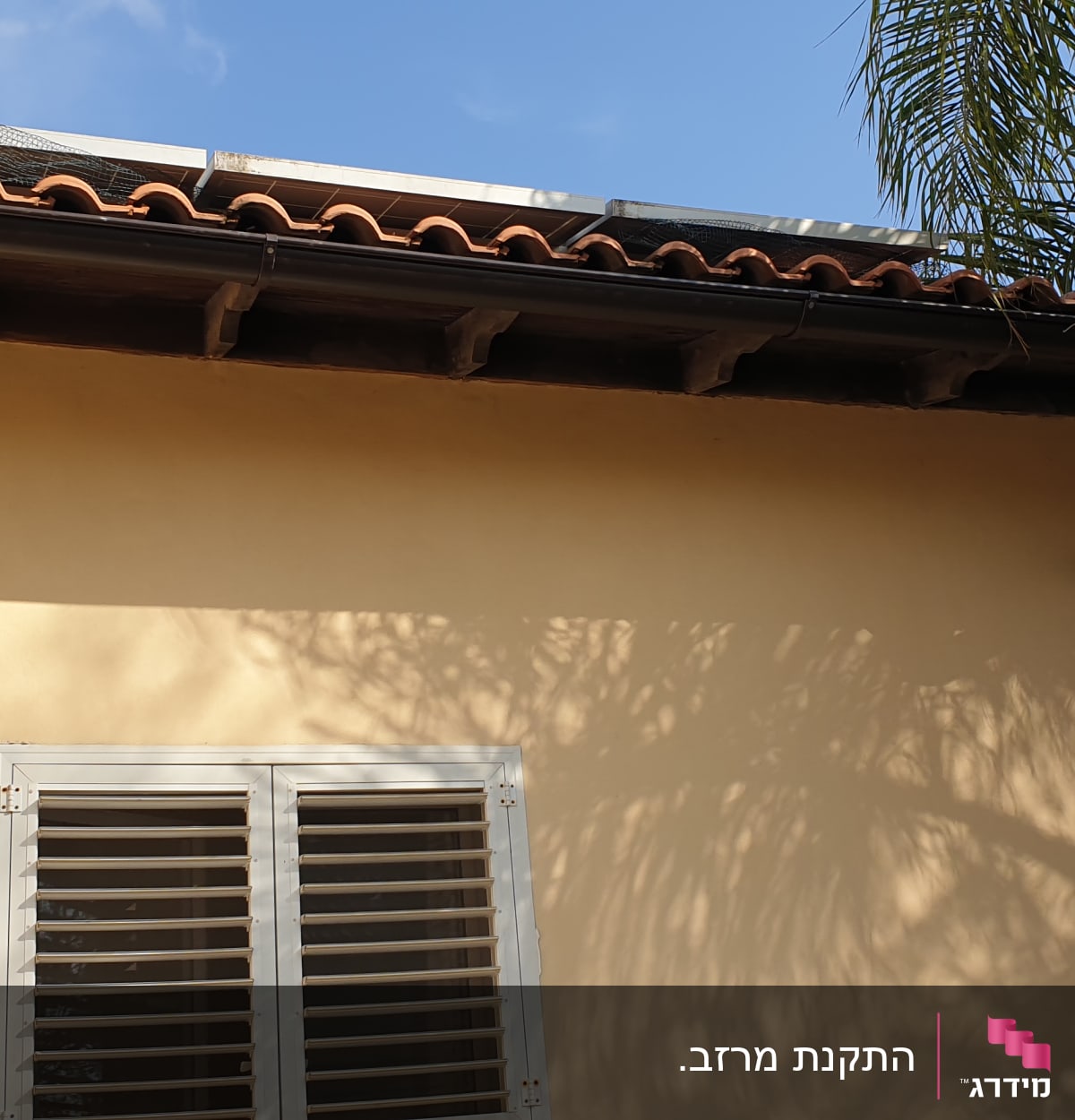 רעפים חומים על גג עם לוחות סולאריים